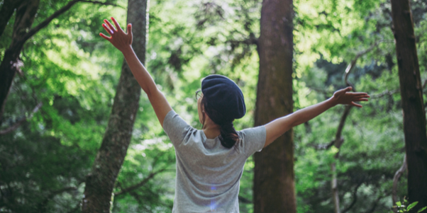 French woman stretching arms in natural forest